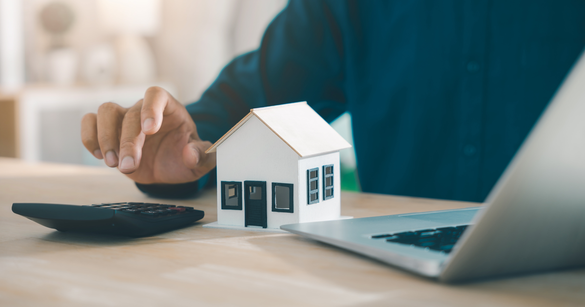 Man achter de laptop maakt berekeningen op een rekenmachine over de lasten van een huis