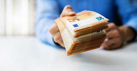 Man met een stapel briefjes van 50 euro in zijn hand